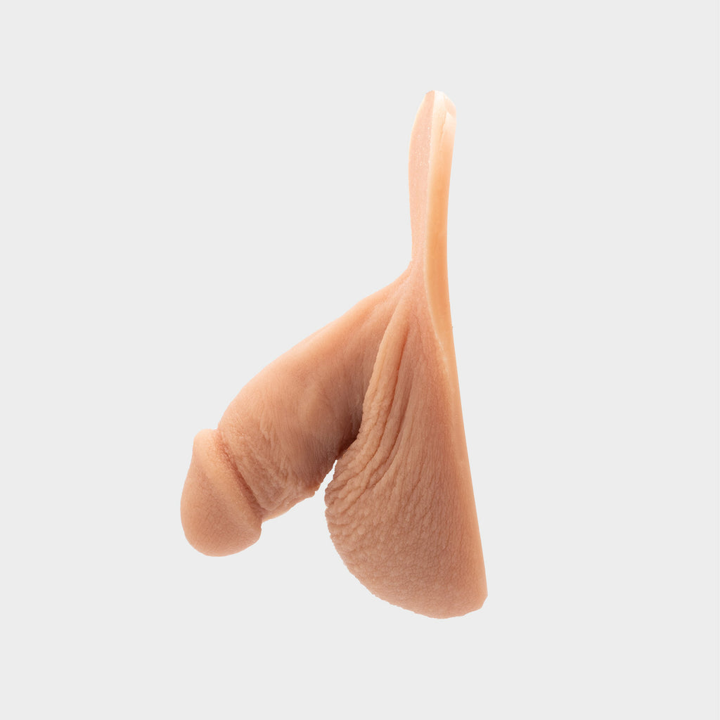 Realistic packer from Banana Prosthetics made of silicone featuring veins, wrinkles, realistic look of a flaccid penis. For trans men, trans masc, nonbinary, ftm people. side view.