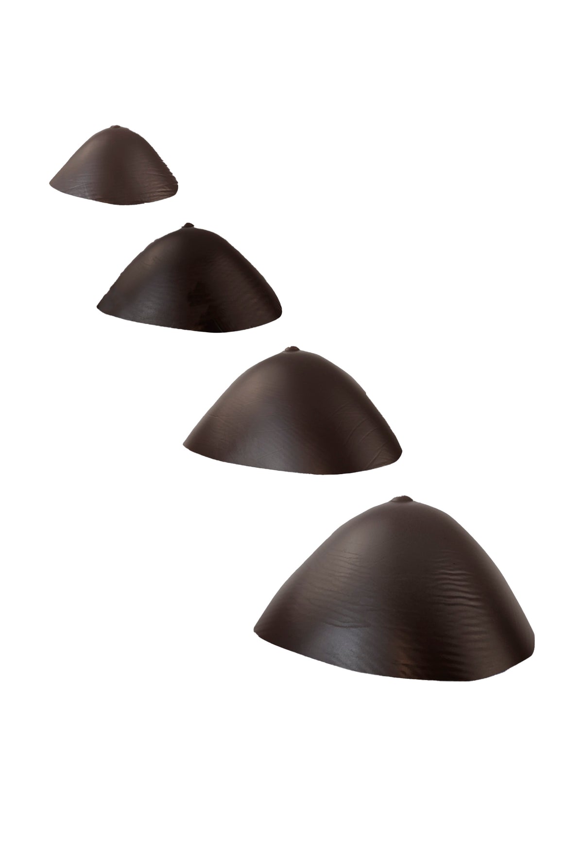Breast forms or silicone realistic breast prostheses for trans women, mtf, drag queens, cosplayers. Dark chocolate color. 4 sizes from A to D cup. Triangular. Diagonal view.