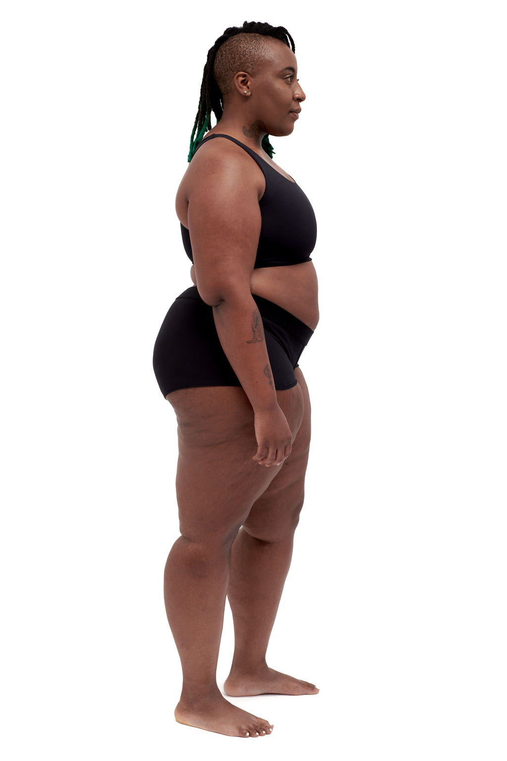 A person wearing a black soft binder from Origami Customs. Side view. Plus size.