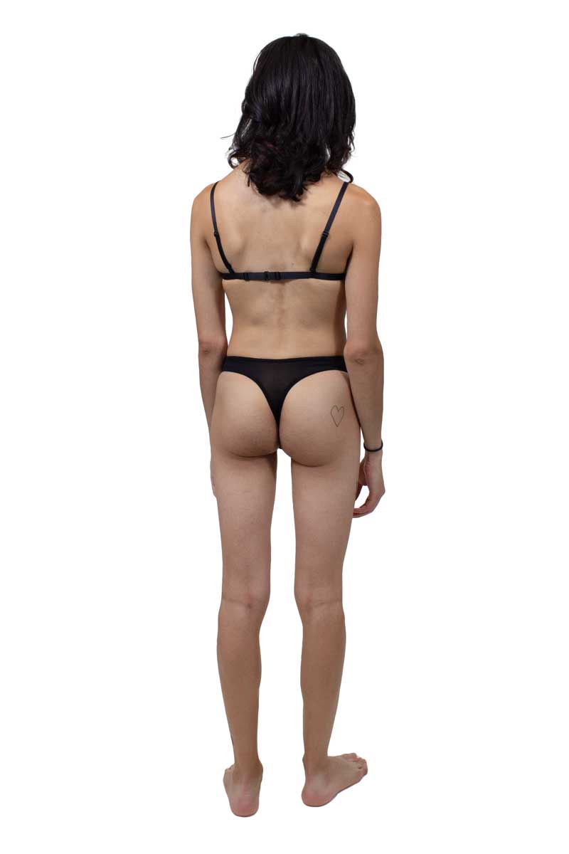 A trans AMAB person wearing tucking thong in black. View from the back.